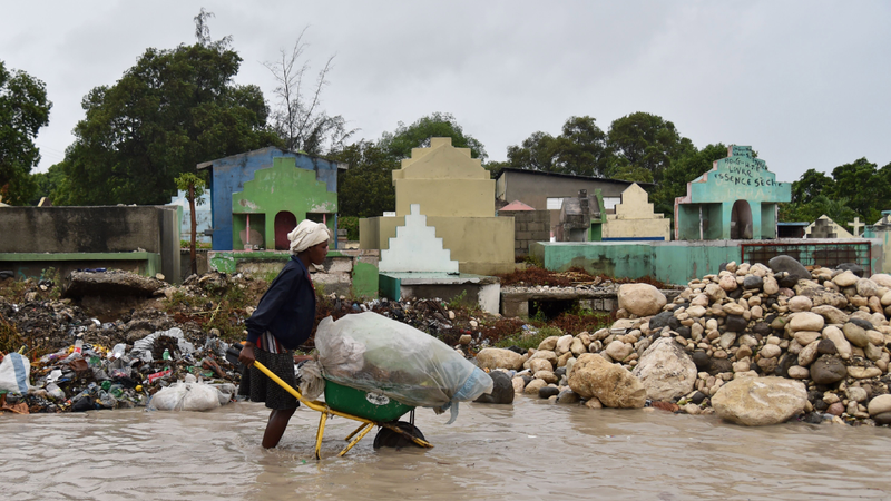 A woman pushes a wheelbarrow while walking in a partially flooded street, in the Haitian capital, Port-au-Prince, on October 4, 2016. Hurricane Matthew made landfall in southwestern Haiti early Tuesday, crashing ashore as a powerful Category Four storm, US weather forecasters said. The National Hurricane Center said Matthew made landfall as an ‘extremely dangerous’ storm near the village of Les Anglais at around 7 am (1100 GMT) with maximum sustained winds of around 145 miles (230 kilometers) per hour. (Image: Getty)